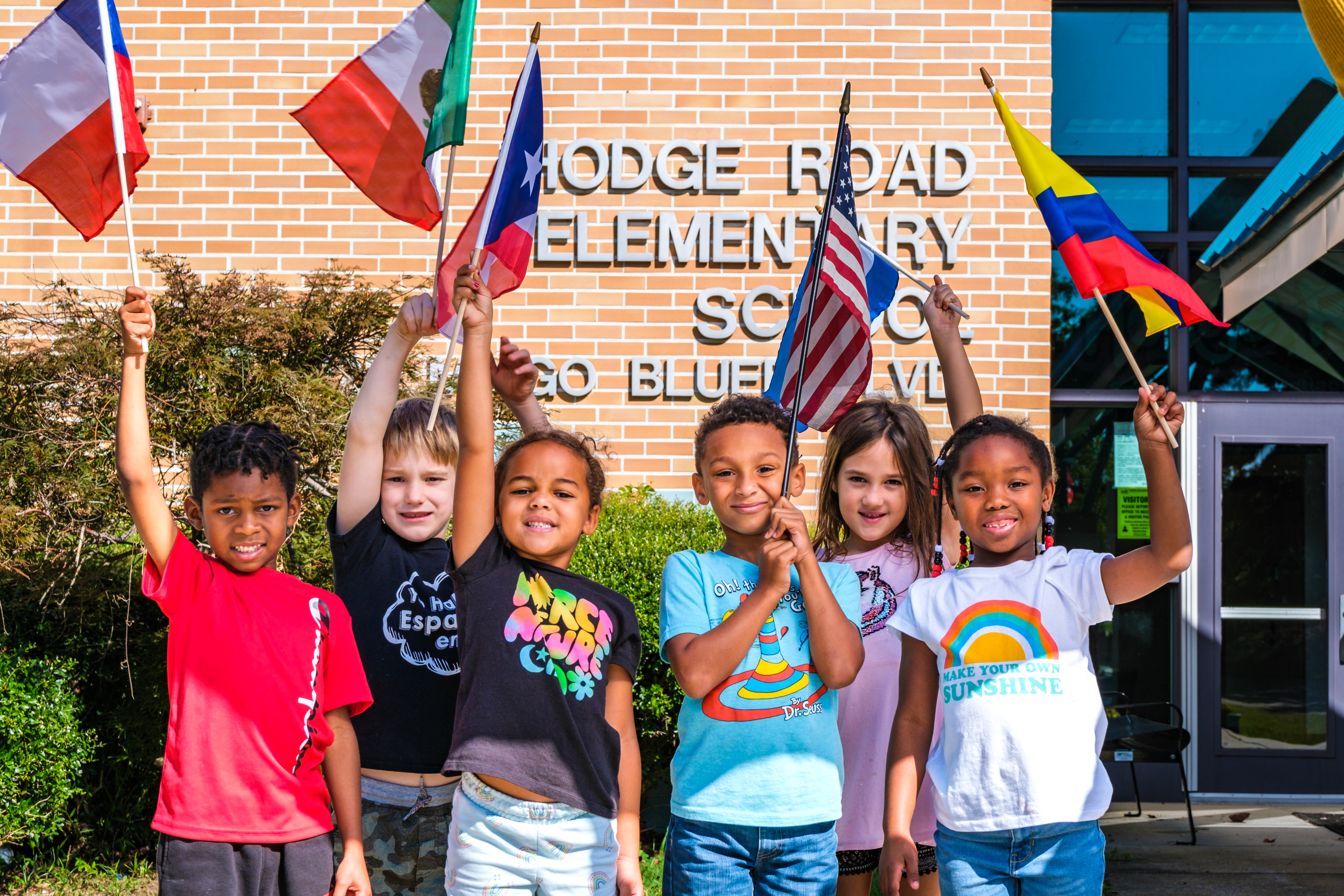 students holding international flags standing in front of Hodge Road Elementary